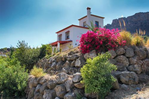 a church on top of a rock wall with flowers at Casa con piscina caminito del rey in Alora