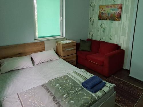 a bedroom with a bed and a red couch at Guest House The House in Plovdiv