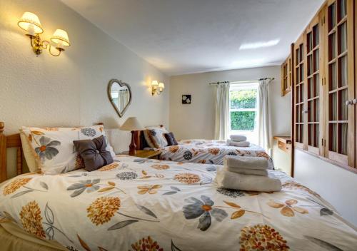 a bedroom with two beds and a mirror at East Cottage in Thwaite