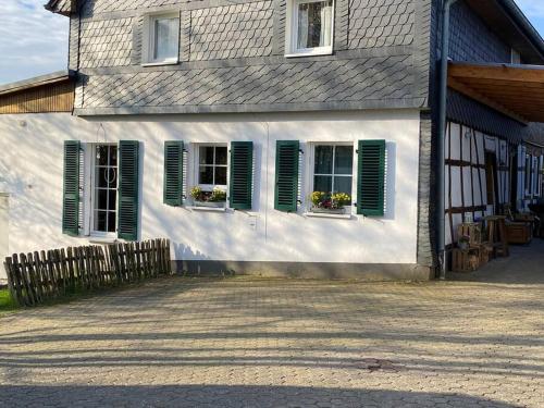 a house with green shutters and flowers in the windows at Ferienwohnung Hückeswagen (Bevertalsperre) in Hückeswagen