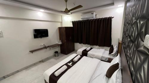 a room with two beds and a tv in it at Hotel Plaza Rooms - Prabhadevi Dadar in Mumbai