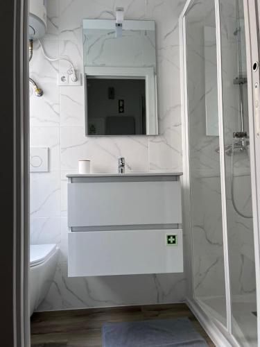La salle de bains blanche est pourvue d'un lavabo et d'un miroir. dans l'établissement CASAS DONA EMILIA, à Vieira de Leiria