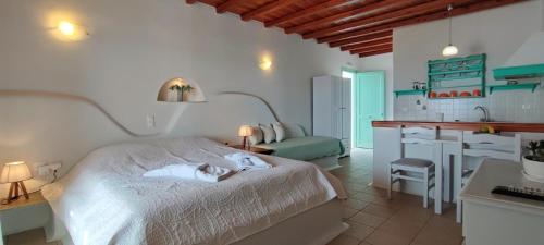 a bedroom with a white bed and a kitchen at Orionides in Tinos