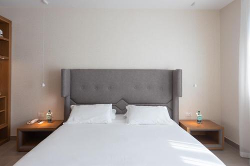 a bedroom with a large white bed with two tables at Mosella Suite Hotel in Sottomarina
