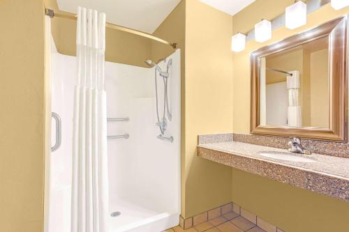 a bathroom with a shower and a sink and a mirror at Days Inn by Wyndham Oklahoma City in Oklahoma City