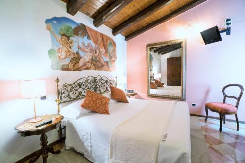 a bedroom with a bed and a table and a mirror at Villa Ducale Hotel & Ristorante in Dolo