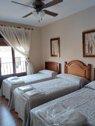 1 dormitorio con 3 camas y ventilador de techo en Casas Mirabel, 