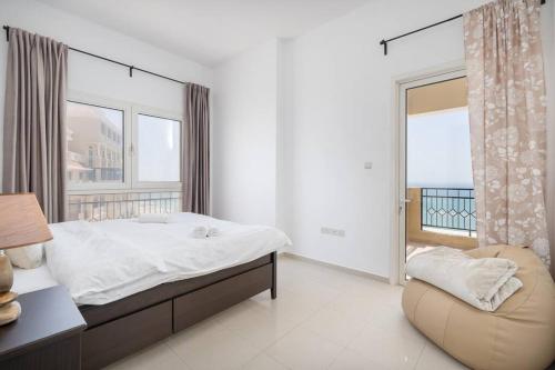 a bedroom with a bed and a chair and a window at Relax in Spacious 2BD with Sea View in Al Hamra in Ras al Khaimah