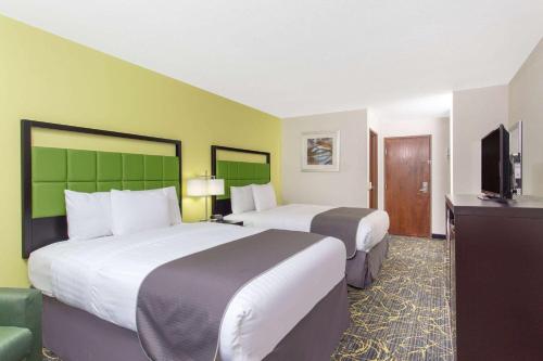 a hotel room with two beds and a flat screen tv at AmericInn by Wyndham Delafield in Delafield