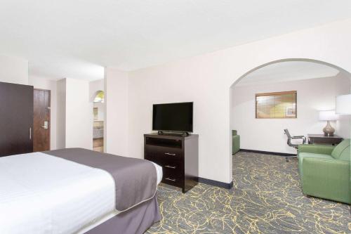 a hotel room with a bed and a flat screen tv at AmericInn and Suites by Wyndham Delafield-Waukesha-Milwaukee in Delafield