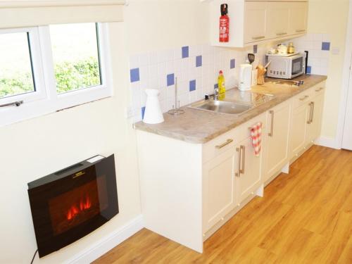 a kitchen with a fireplace in the wall at Dove Meadow in Denstone