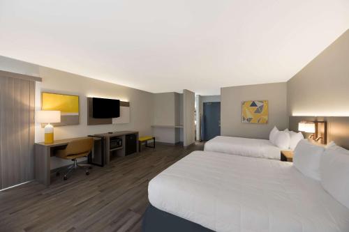 a hotel room with two beds and a desk at Quality Inn & Suites Artesia in Artesia