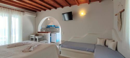 1 dormitorio blanco con 1 cama y cocina en Orionides en Tinos Town