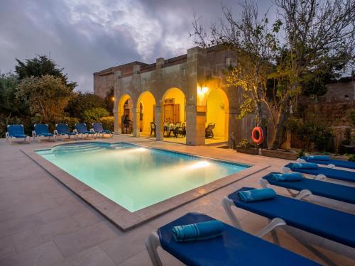 einen Pool mit Liegestühlen und ein Gebäude in der Unterkunft Dar Is-Sultan Farmhouse in Il-Wilġa