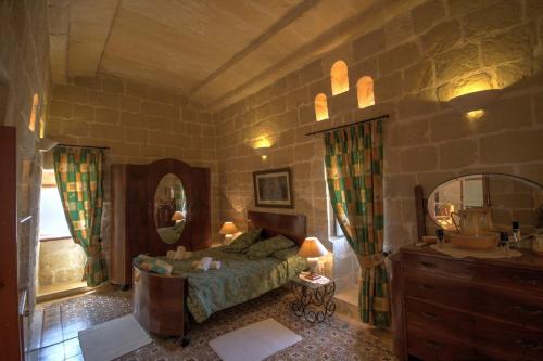 ein Schlafzimmer mit einem Bett, einem Waschtisch und einem Spiegel in der Unterkunft Dar Is-Sultan Farmhouse in Il-Wilġa