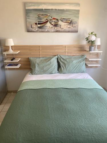 a bed with a green comforter and two boats at Nissi Breeze in Ayia Napa