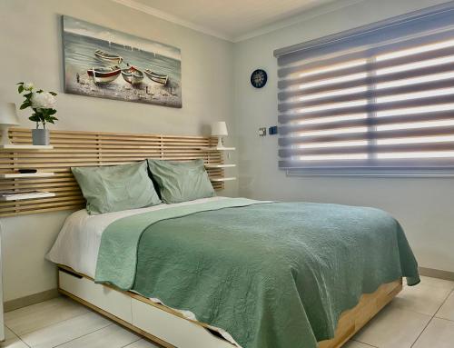 a bedroom with a bed with a green comforter and a window at Nissi Breeze in Ayia Napa