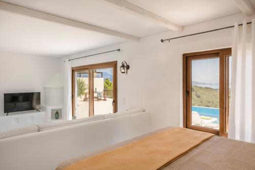 a bedroom with a bed and a tv and a window at Akrolithos Villas in Kouvaláta