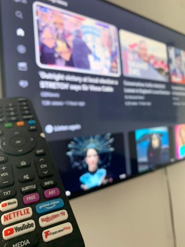 a remote control sitting in front of a tv at AK Serviced Apartments - Exclusive Two-Bedroom Apartment in Cardiff