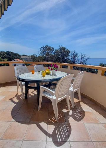a table and four chairs on a patio with a view of the ocean at Apartments MULOBEDANJ in Lun
