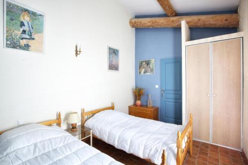 deux lits dans une chambre aux murs bleus dans l'établissement La Cerisaie, maison spacieuse en Lubéron, à Saint-Martin-de-Castillon