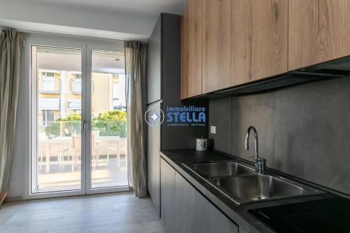 een keuken met een wastafel en een glazen schuifdeur bij Condominio Trento in Lido di Jesolo