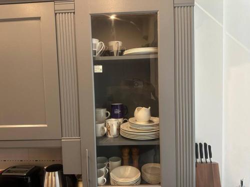 a cupboard with plates and cups and dishes in it at 5 bedroom House SE6 in Hither Green