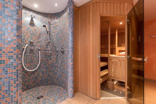 y baño con ducha de azulejos azules. en Hotel Bergfried & Schönblick, en Bad Reichenhall