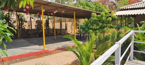 a patio with awning in a garden with plants at Kastur Farm in Karjat
