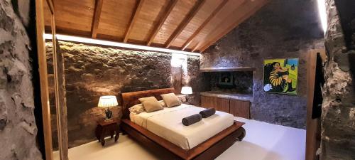 a bedroom with a bed and a stone wall at Casa dos Gatos in Calheta