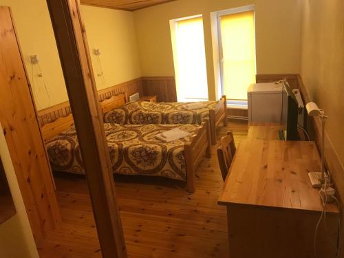 Cette petite chambre comprend deux lits et un bureau. dans l'établissement Puhkekeskus SUVI, à Karjamaa