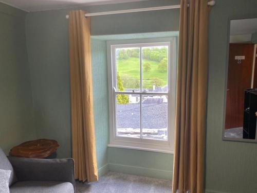 ein Wohnzimmer mit einem Fenster und einem Stuhl in der Unterkunft Kings Arms in Llandysul