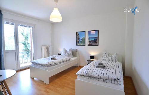 two beds in a room with white walls and wood floors at BEGE APARTMENTS: PERFECT FOR COMPANIES in Gelsenkirchen