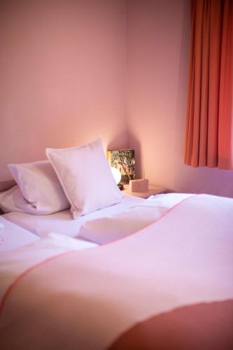 a bedroom with two beds with white sheets and a lamp at DAS SCHÖNE LEBEN Pop-Up Hotel in Hornberg