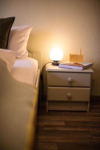 a lamp on a night stand next to a bed at DAS SCHÖNE LEBEN Pop-Up Hotel in Hornberg