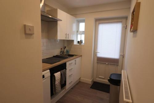 a kitchen with white cabinets and a sink and a window at Stylish one bed apartment with off road parking in Birmingham