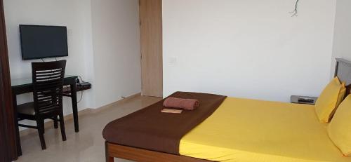 Dormitorio con cama, escritorio y TV en P N A Apartments - Manpada, en Thane
