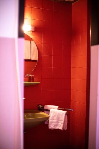 a red tiled bathroom with a sink and a mirror at DAS SCHÖNE LEBEN Pop-Up Hotel in Hornberg
