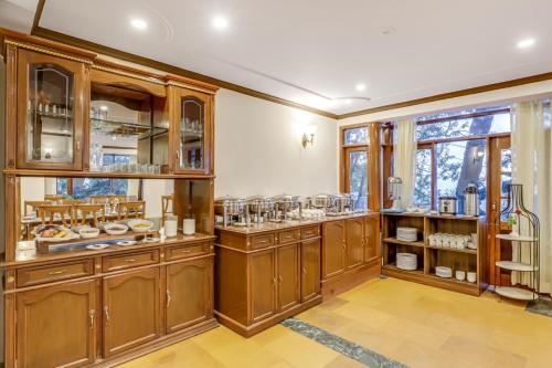 a kitchen with wooden cabinets and a large window at Summit Le Royale Hotel, Shimla in Shimla