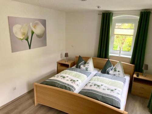 1 dormitorio con 1 cama con cortinas verdes y ventana en Ferienwohnung "Am Kirchsteig", en Kurort Gohrisch