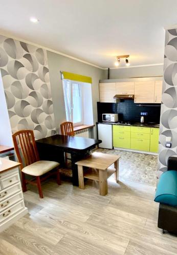 a kitchen with a table and two chairs and a kitchen with yellow cabinets at Апартаменти на Поштовій площі in Kyiv