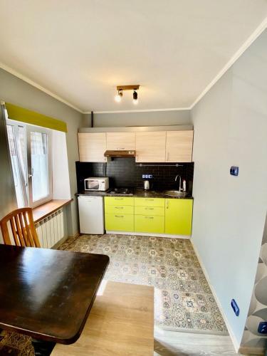 a kitchen with yellow cabinets and a table in it at Апартаменти на Поштовій площі in Kyiv