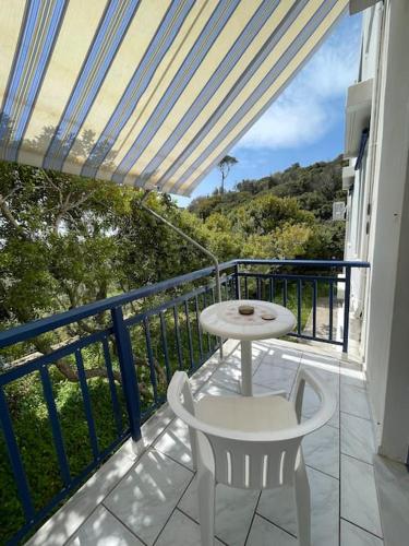 een balkon met een tafel en een witte tafel en stoel bij Seagulls in Chios