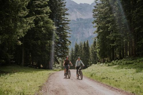 two people riding bikes down a dirt road at G'sund & Natur Hotel Die Wasnerin - Adults Only in Bad Aussee