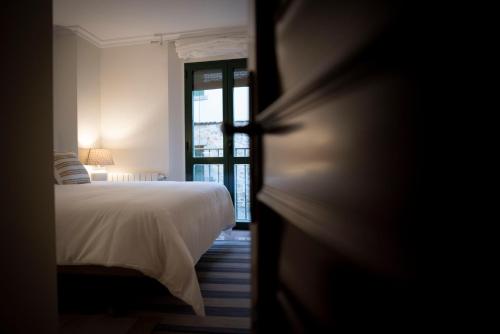 a bedroom with a white bed and a window at Apartamento Exterior 2 dormitorios en CENTRO HISTÓRICO in San Lorenzo de El Escorial