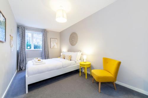 a bedroom with a white bed and a yellow chair at Lovely 2 BR Notting Hill flat wgarden in London