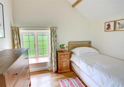 a bedroom with a bed with a dresser and a window at Coach Cottage in Gilling East