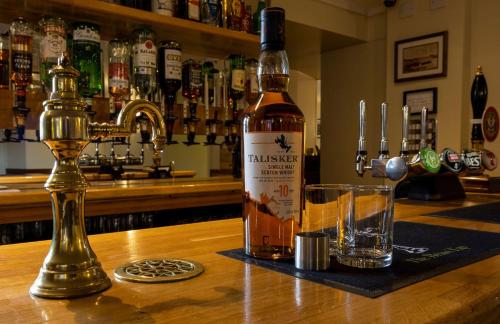a bottle of whiskey sitting on a bar with a glass at The Tongue Hotel in Tongue