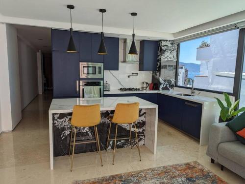 una cocina con armarios azules y 2 sillas de bar en Ocean View Penthouse in P.V. Romantic Zone en Puerto Vallarta
