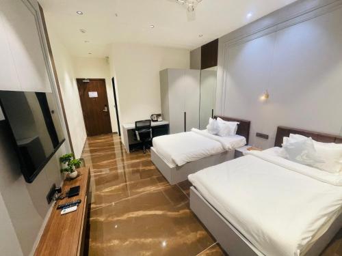 a hotel room with two beds and a television at VITS Jamnagar in Jamnagar